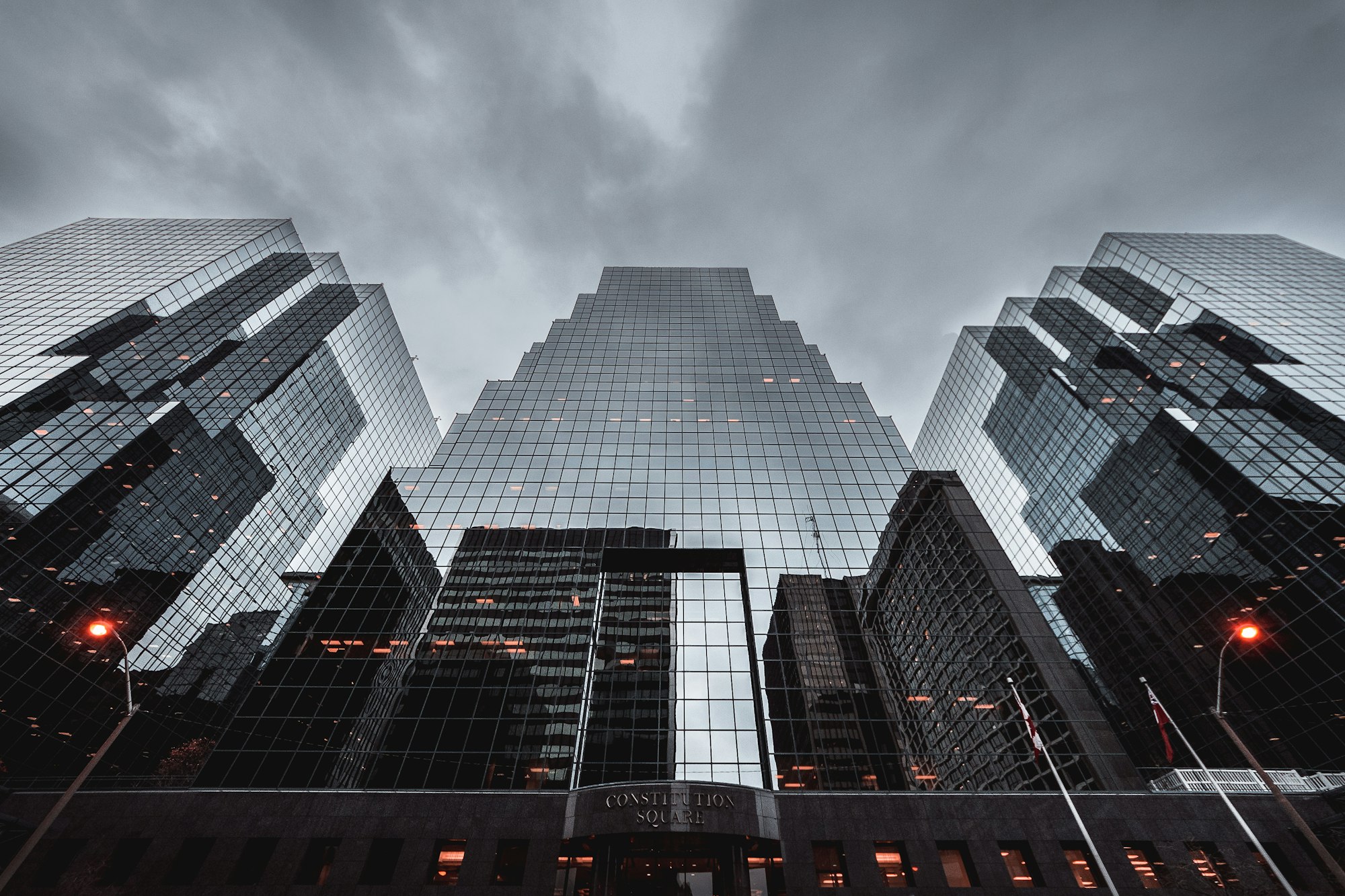 Generate an image of: Looking straight up at a brutalist concrete skyscraper, perfectly symmetric, harsh shadows, bright yellow geometry accent
